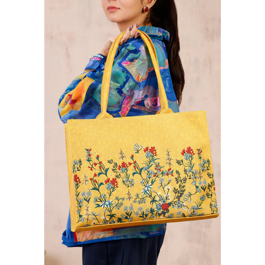 Bagwati yellow floral canvas tote bag with handles, modeled by a woman in a colorful shirt.