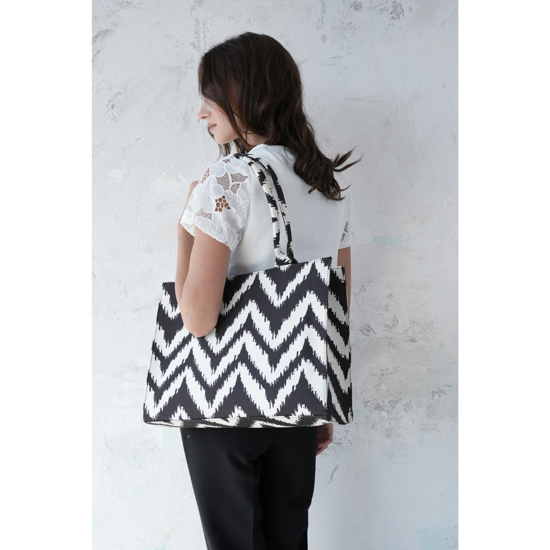 Woman carrying Bagwati black and white chevron canvas tote bag against light wall