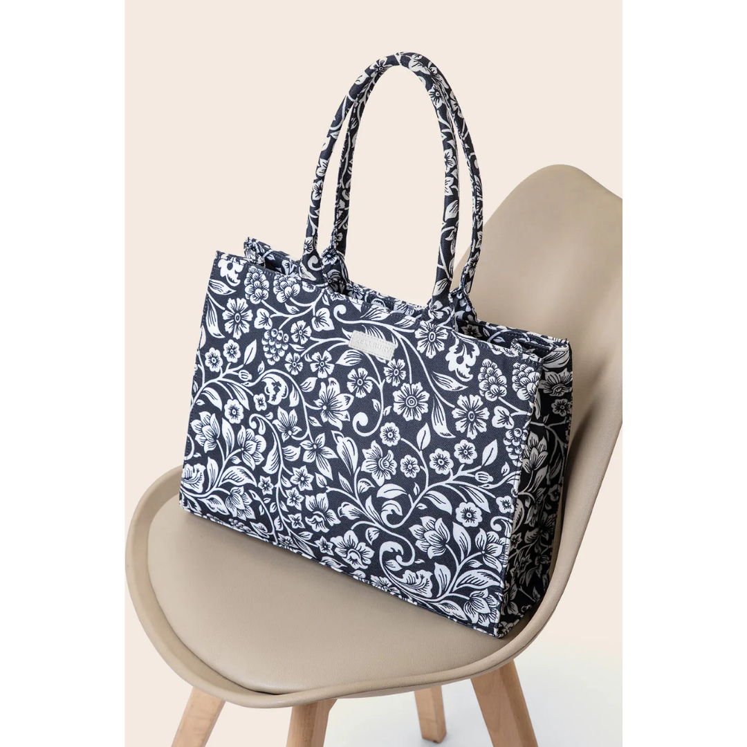 Bagwati black canvas tote bag with white floral print on chair, elegant handbag design