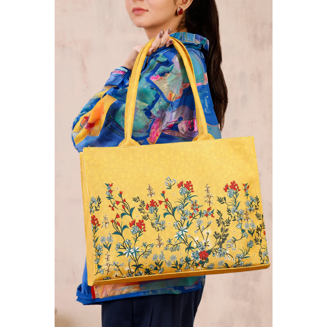 Bagwati yellow floral canvas tote bag with handles, modeled by a woman in a colorful shirt.