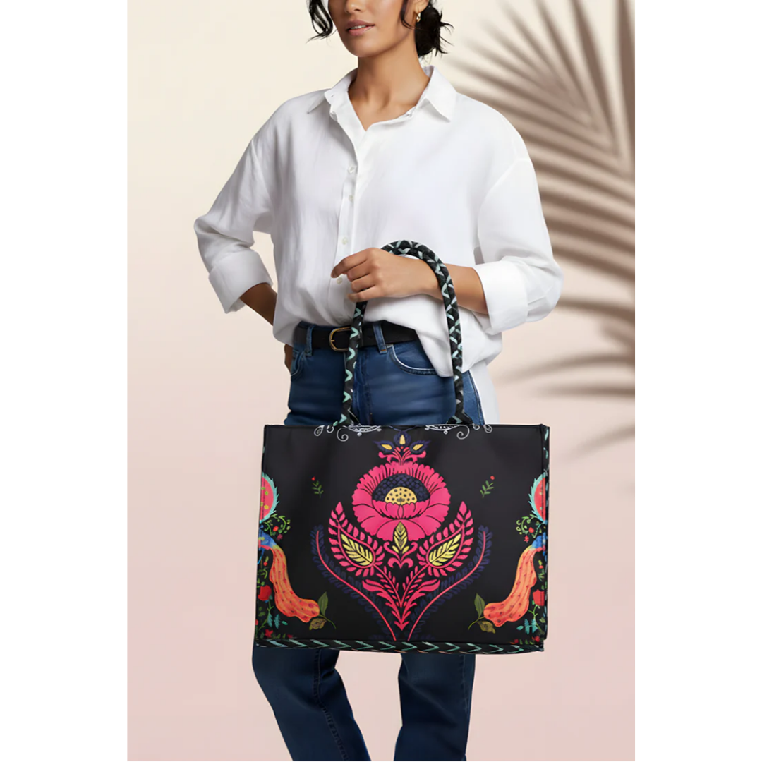 Bagwati Carnival Canvas Tote in black with colorful floral print, held by woman in white shirt