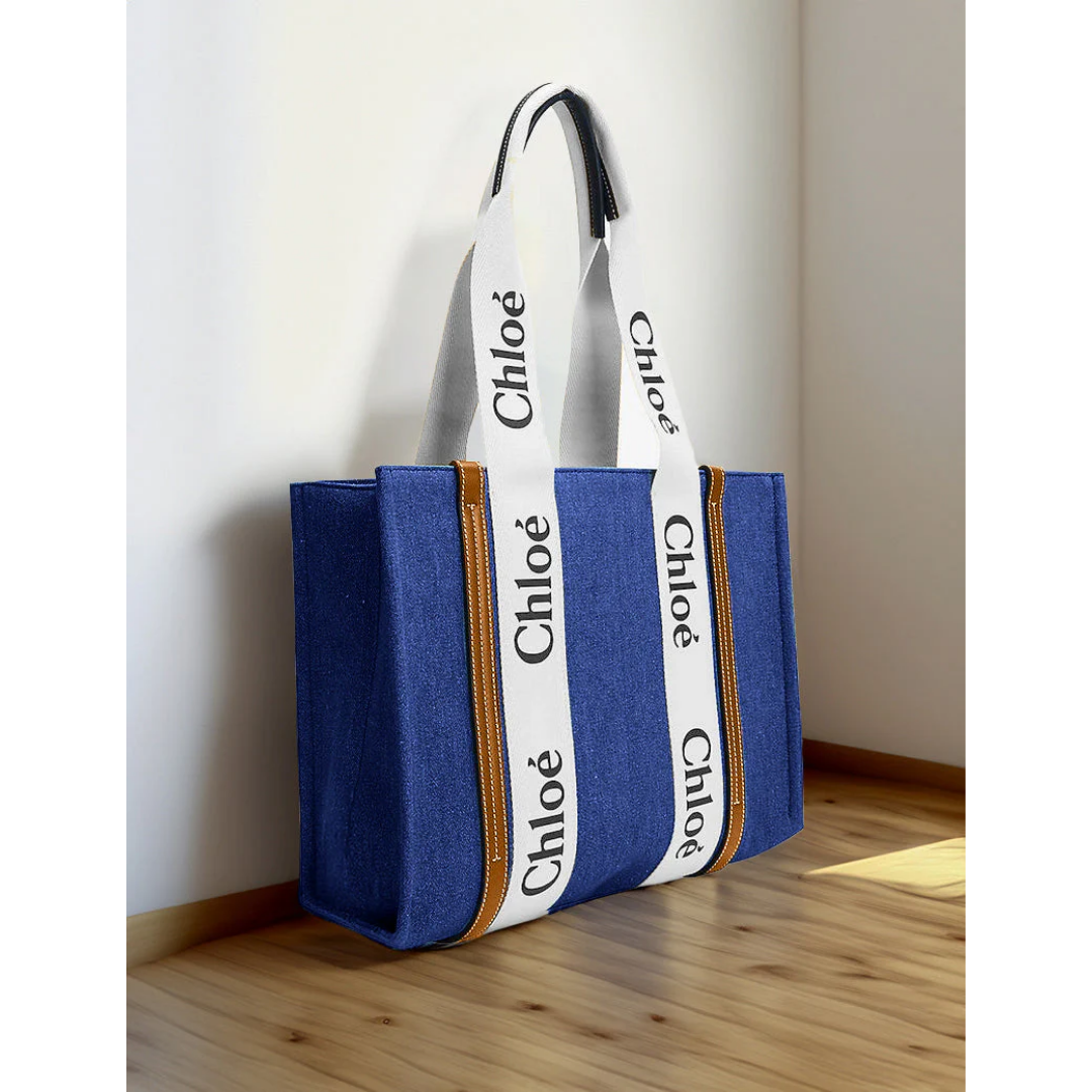 Blue canvas tote bag with white branded straps, premium design, on wooden floor