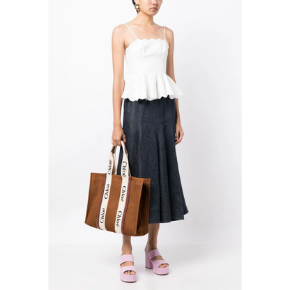 Woman holding a dark brown Chloe canvas tote bag with white logo handles, Bagwati handbags