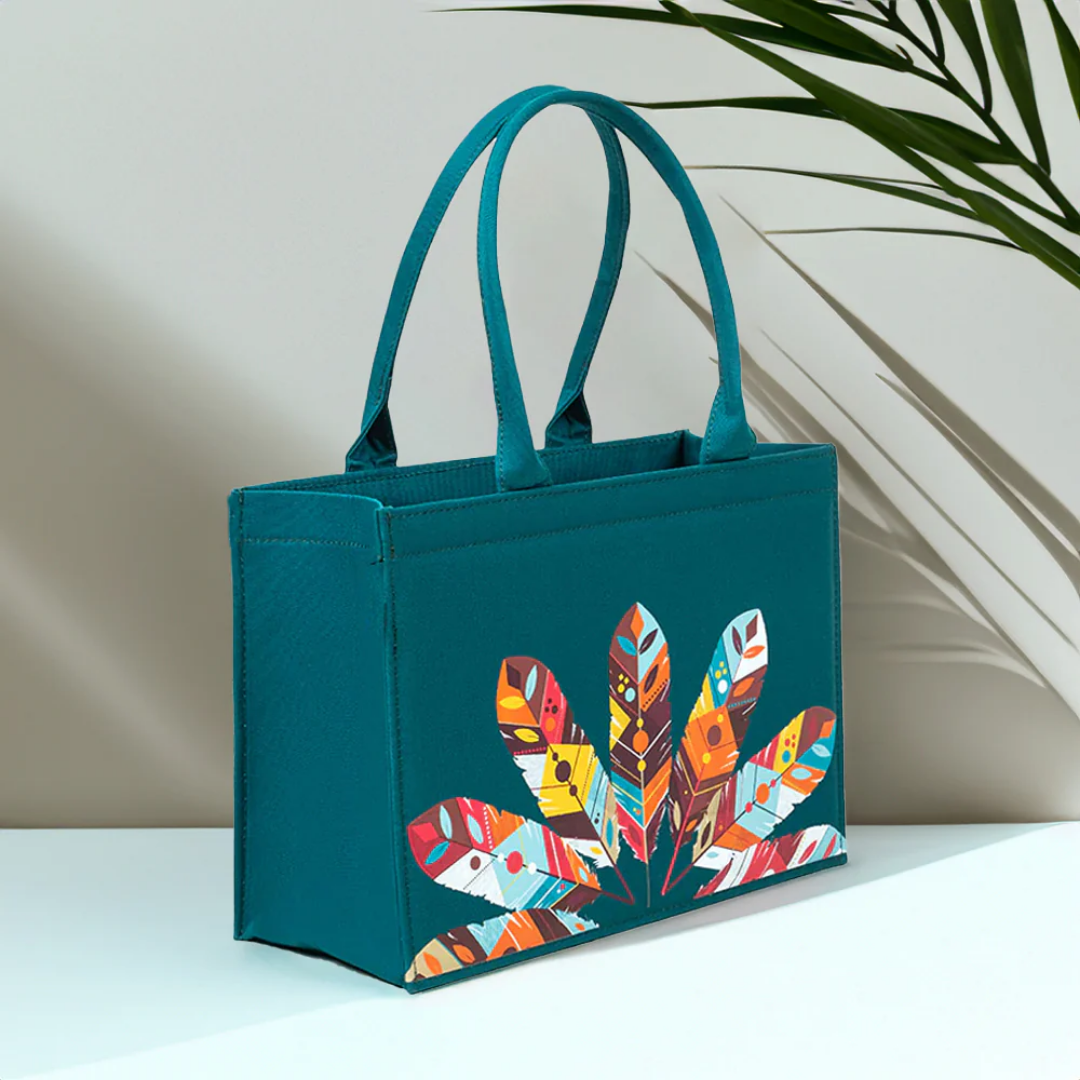 Teal mini canvas tote bag with colorful feather print, Bagwati handbag on white surface