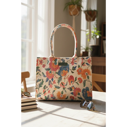 Bagwati beige floral canvas tote bag on table with sunlight, books, sunglasses, and indoor plants
