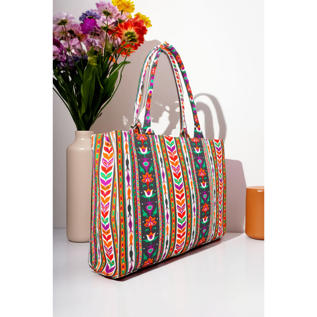 Colorful floral patterned canvas tote bag by Bagwati, displayed beside a vase of flowers.