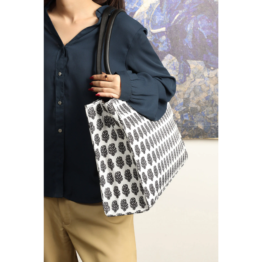 Bagwati monochrome canvas tote bag with black leaf print, worn on shoulder