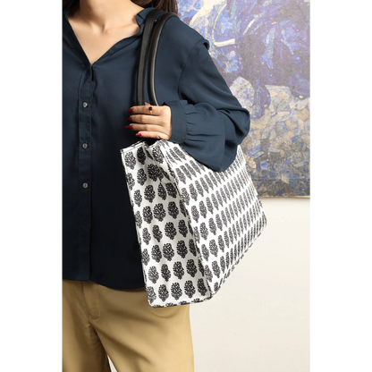 Bagwati monochrome canvas tote bag with black leaf print, worn on shoulder