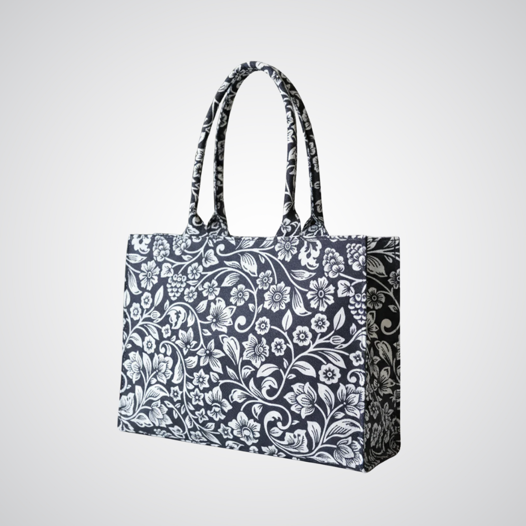 Black and white floral canvas tote bag by Bagwati with double handles on a plain background.